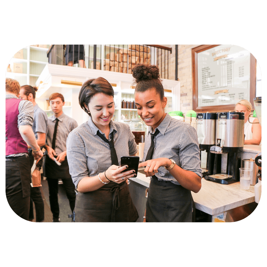 Restaurant employees looking at schedule on phone.