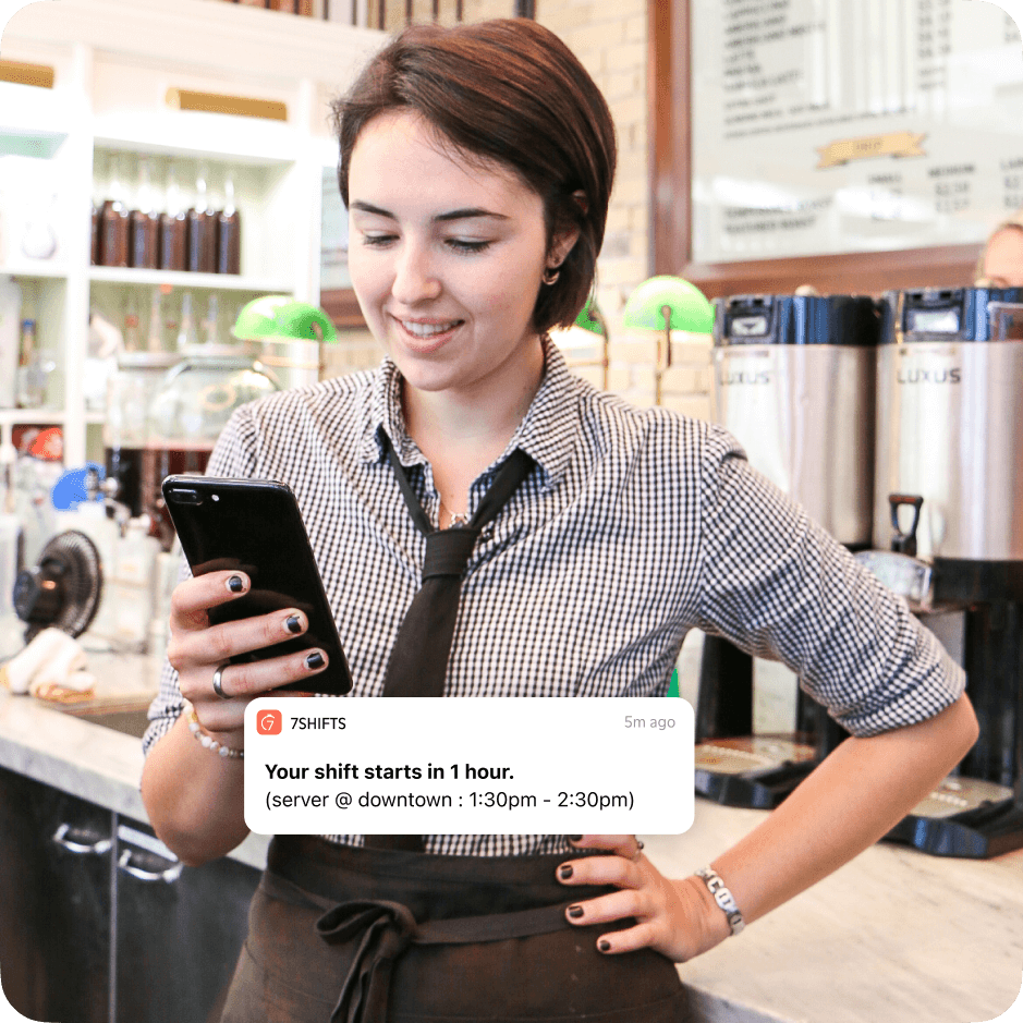 Restaurant employee checking mobile phone for shift notifications.